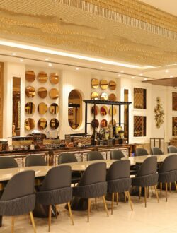 Luxurious and spacious hotel dining room with elegant decor and rich golden accents, offering a lavish ambiance.
